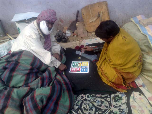  Prakash plays ludo with another patient at the pavement outside AIIMS canteen.